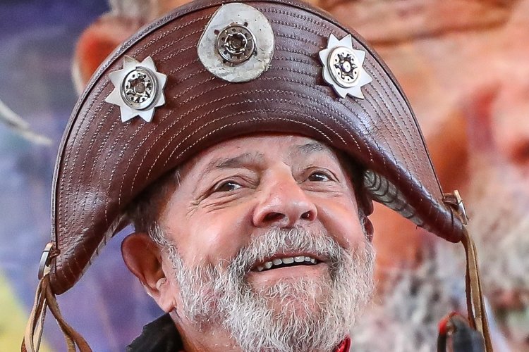 O presidente Luiz Inácio Lula da Silva sorri para a câmera usando um chapéu de couro marrom típico do cangaço, adornado com estrelas metálicas.